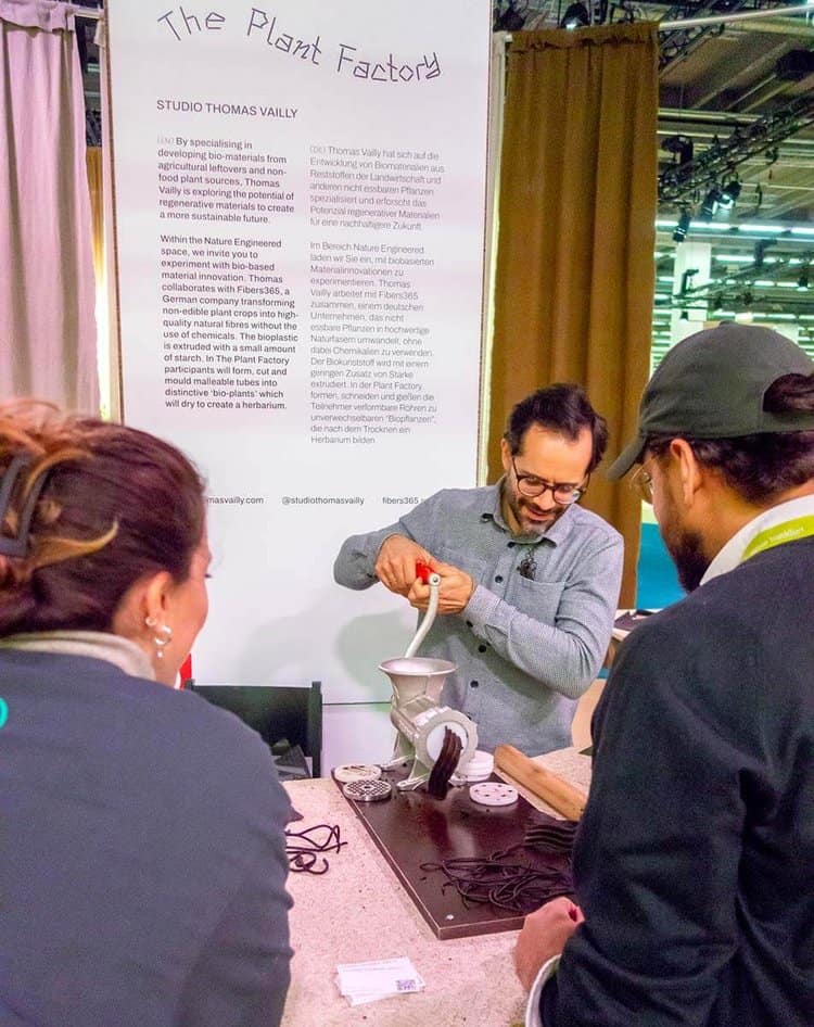 Man extruding malleable biomaterial with a crank device as onlookers watch