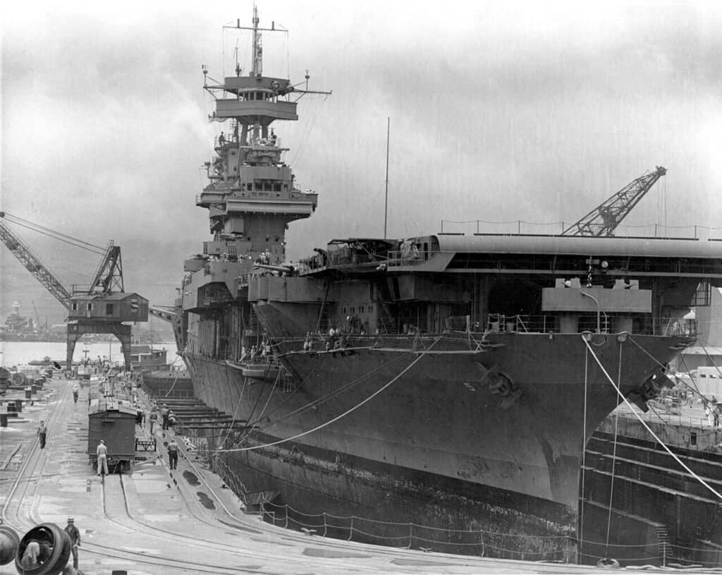 Aircraft carrier USS Yorktown in drydock at Pearl Harbor Naval Shipyard with workers and cranes alongside, May 1942